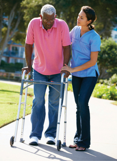 physical therapist helping senior man walk using walker