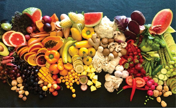 large variety of fruits and veggies laid out on a table sorted by color