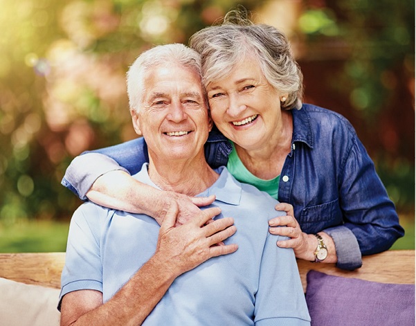older adult couple embracing and smiling for photo in the park
