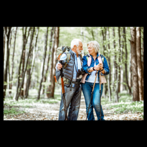 senior couple hiking in the woods with hiking bags and hiking sticks.