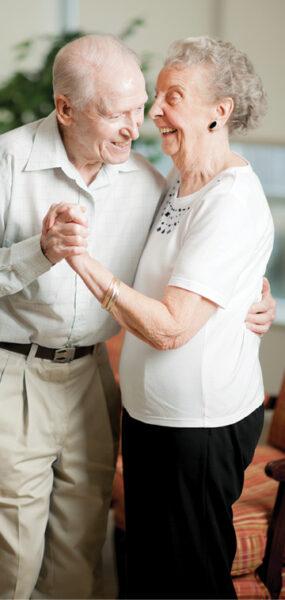 older male and female couple smiling and dancing hand in hand