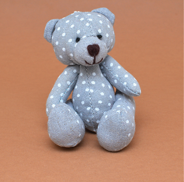blue teddy bear posed for photo on light brown background