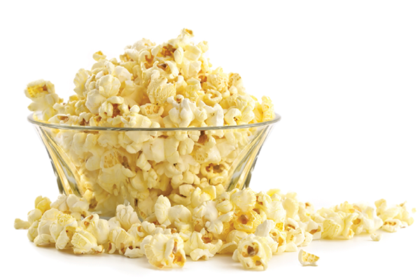 Large glass bowl of popcorn with popcorn overflowing on the side